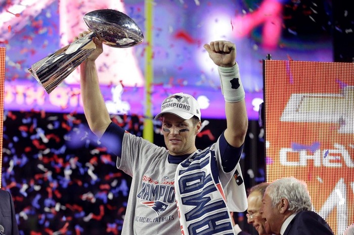 Tom Brady holding the Super Bowl trophy with confetti falling