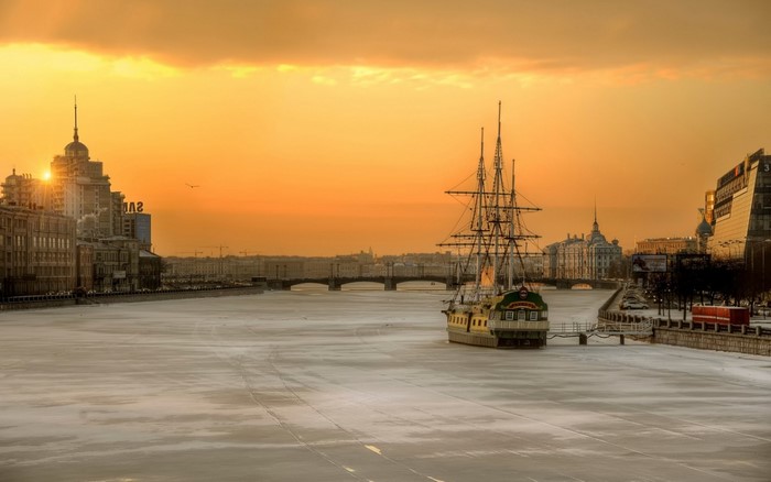 Tall ship on frozen river at sunset in St. Petersburg, Russia