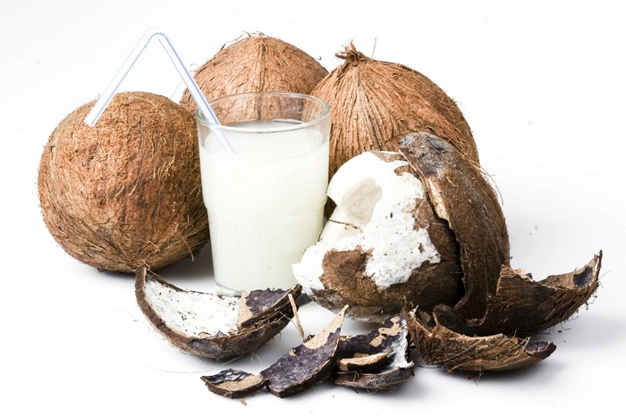 Coconut milk in a glass with coconuts and shells