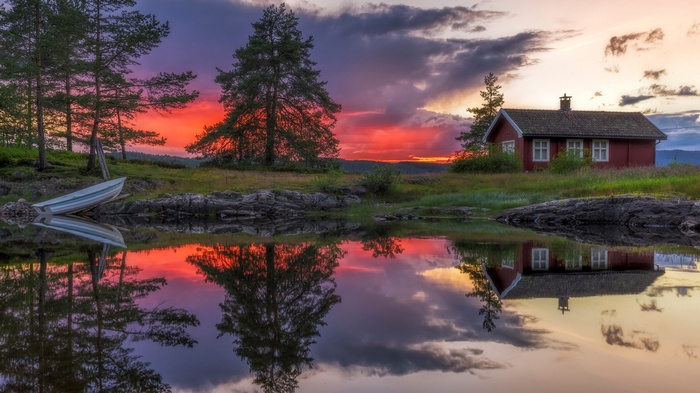 Red cabin by a lake at sunset with reflection