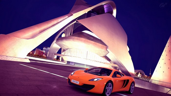 Orange McLaren MP4-12C in front of modern architecture