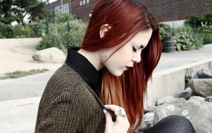 Woman with red hair wearing a gold cardigan