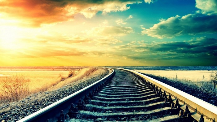 Train tracks curving through a landscape at sunset