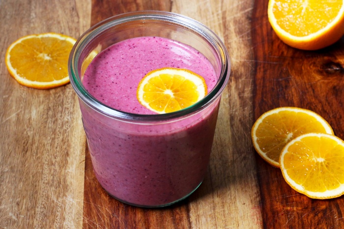 Berry smoothie with orange slices on a wooden board