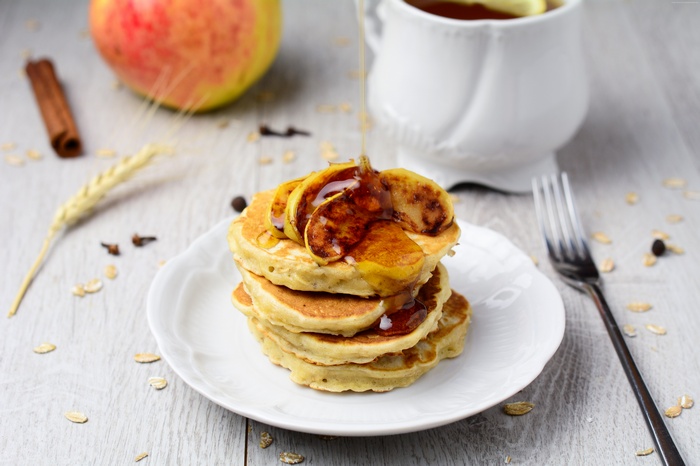 Stack of pancakes with apple slices and syrup