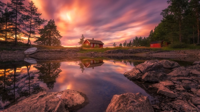 Red cabin by a lake at sunset