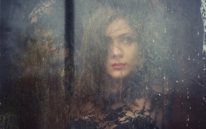 Woman behind dirty glass with lace