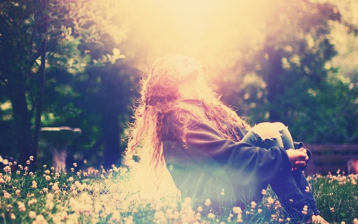 Woman sitting in a meadow with sunlight