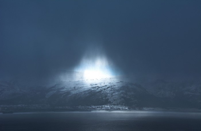 Sunlight beam over snowy mountains and sea