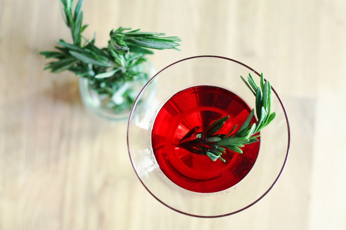 Red cocktail with rosemary garnish