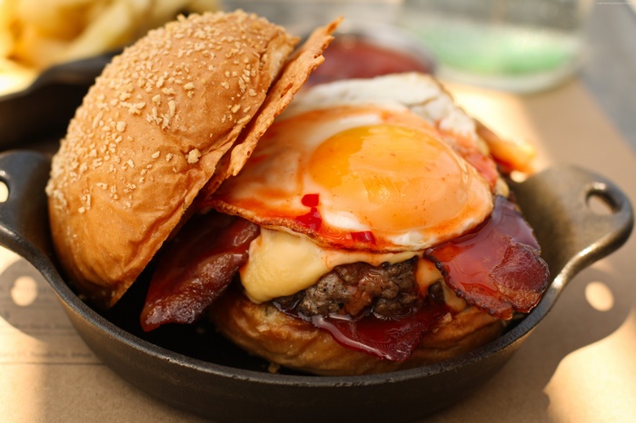Burger with fried egg and bacon in a pan