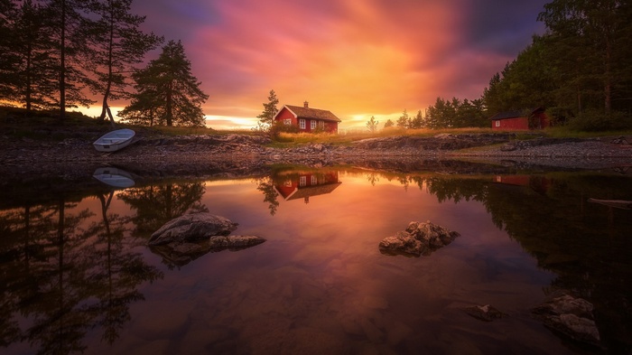 Red cabins by a lake at sunset