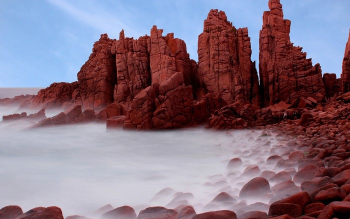 Red rock formations on a misty coastline with long exposure sea
