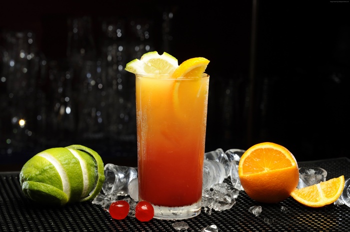 Cocktail with orange, lime, and cherries on ice