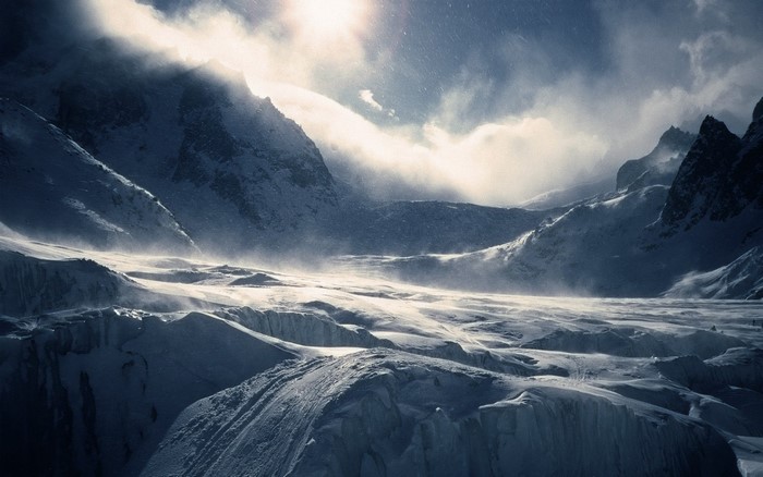 Snowy mountain range with sunlight and clouds