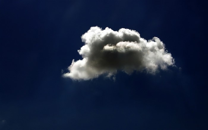 A single cumulus cloud against a dark blue sky
