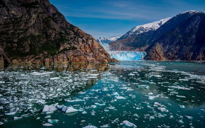 Glacier and icebergs in a fjord with mountains