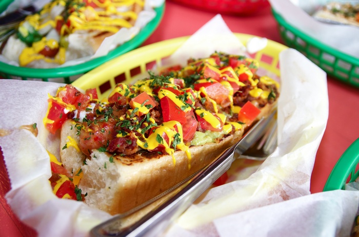 Hot dog with tomatoes, bacon, and mustard