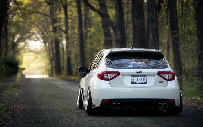 White Subaru Impreza WRX STi on a tree-lined road