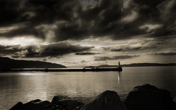 Sepia toned lighthouse on a pier at dusk
