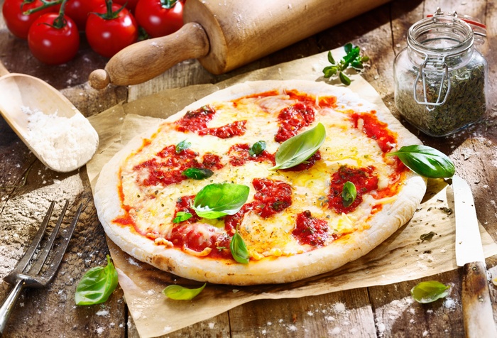 Pizza with tomatoes and basil on a wooden table