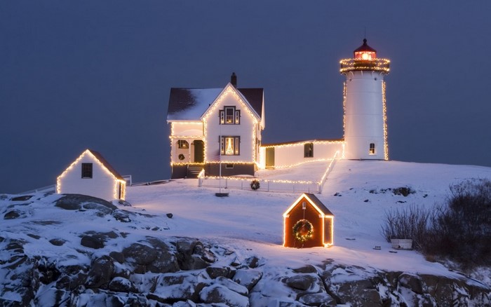 Lighthouse decorated with Christmas lights in the snow at night