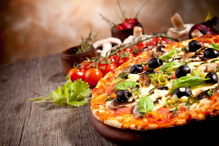 Pizza with olives, mushrooms, and tomatoes on a wooden table