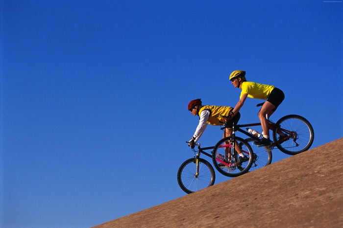 Two people riding a tandem bicycle uphill
