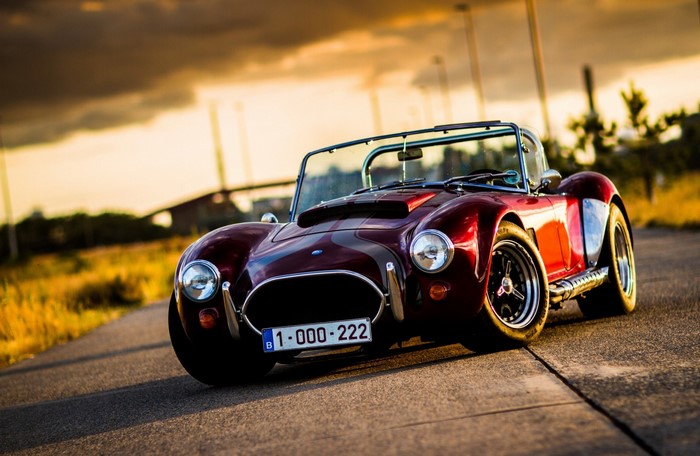 Red Shelby Cobra convertible sports car on road