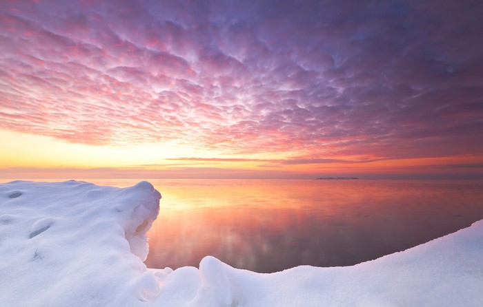 Snowy shore at sunset with colorful sky reflection