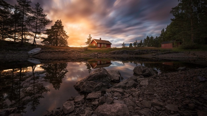 Red cabin by a lake at sunset