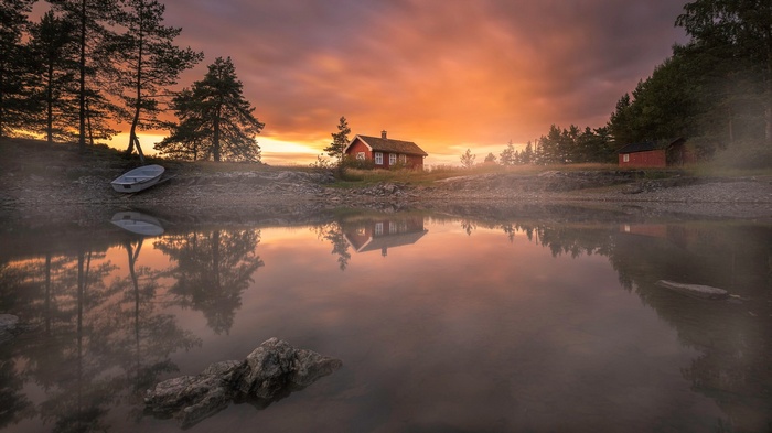 Red cabin by a misty lake at sunset