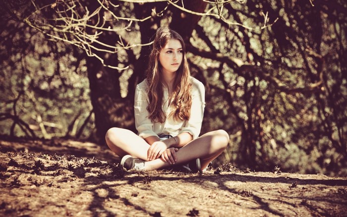 Young woman sitting cross-legged in a forest