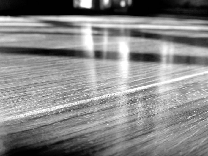 Monochrome close-up of a wooden floor with reflections
