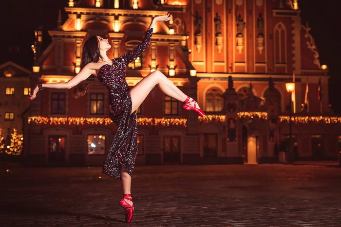Ballerina dancing in front of a historic building at night