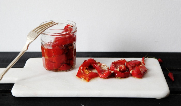 Jar of sun-dried peppers with fork and chili peppers