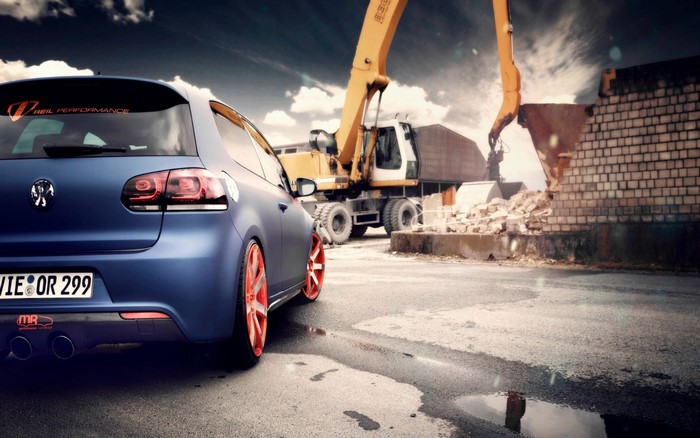 Blue Volkswagen Golf R32 with orange rims at construction site