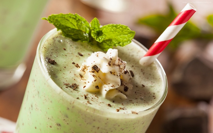 Mint chocolate chip milkshake with whipped cream and mint leaves