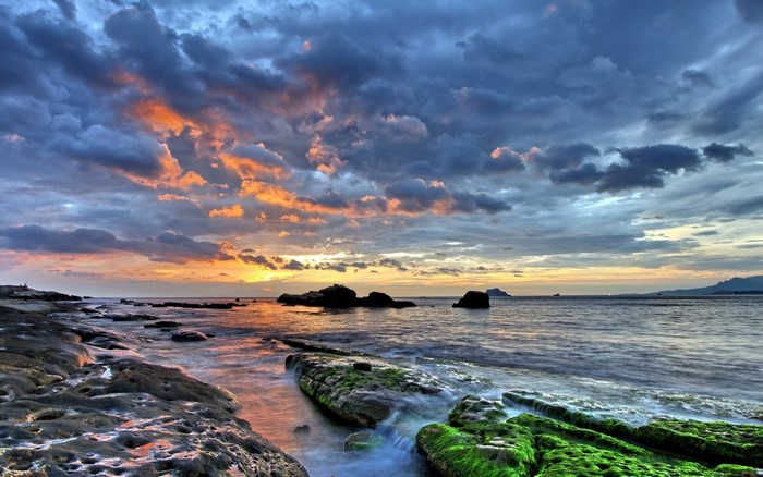 Sunset over rocky shore with dramatic clouds