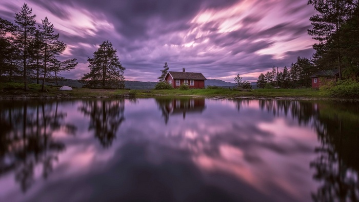 Red cabin by a lake with purple clouds