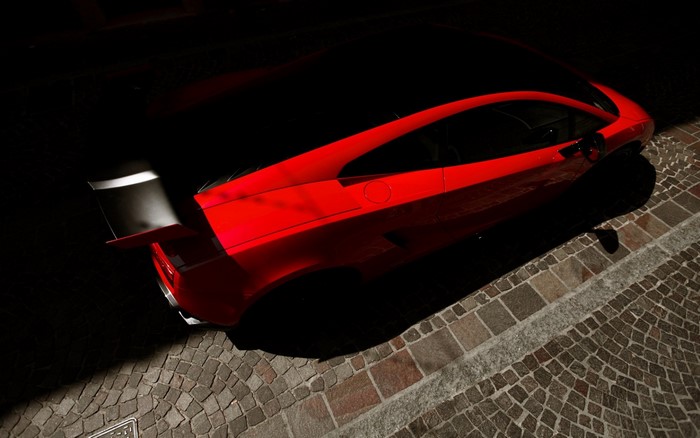 Red Lamborghini sports car parked on cobblestone street
