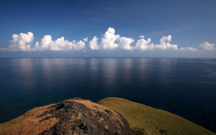 Ocean horizon with clouds over a grassy cliff