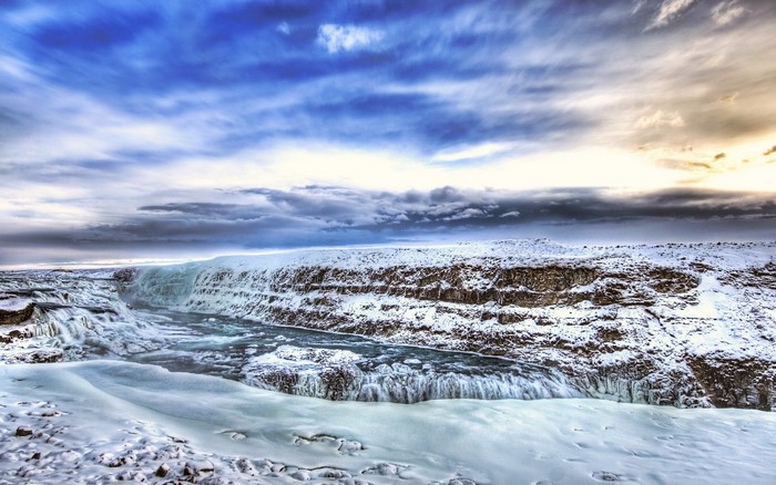 Snowy waterfall landscape with dramatic sky