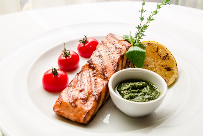 Grilled salmon with cherry tomatoes, lemon, and pesto sauce