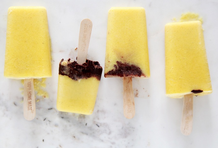 Yellow popsicles with chocolate chunks on sticks