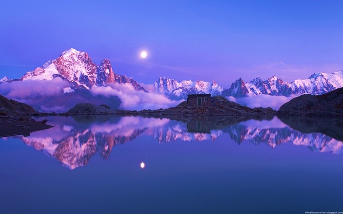 Snow-capped mountains reflected in a lake at dusk