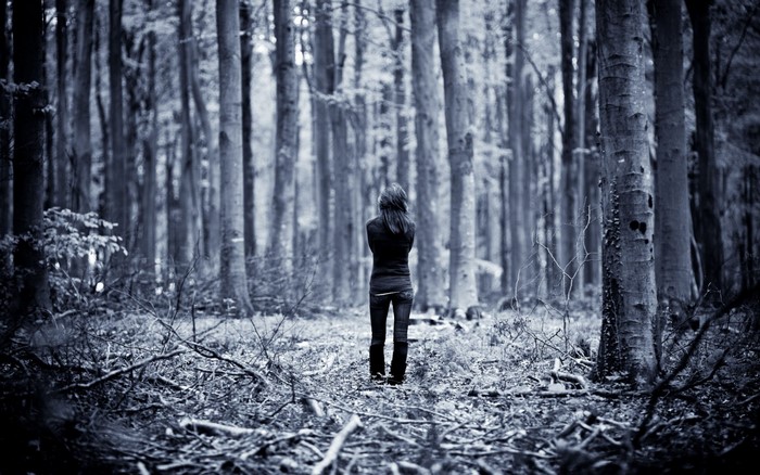 Woman standing alone in a dark forest