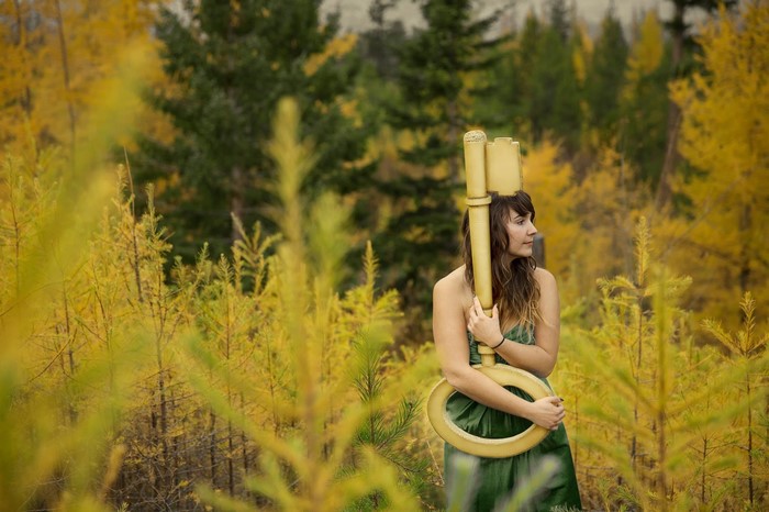 Woman holding a large golden key in a forest