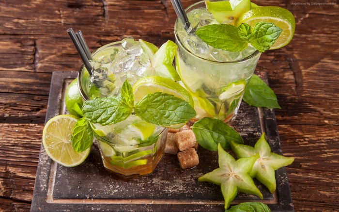 Two mojito cocktails with lime, mint, and star fruit