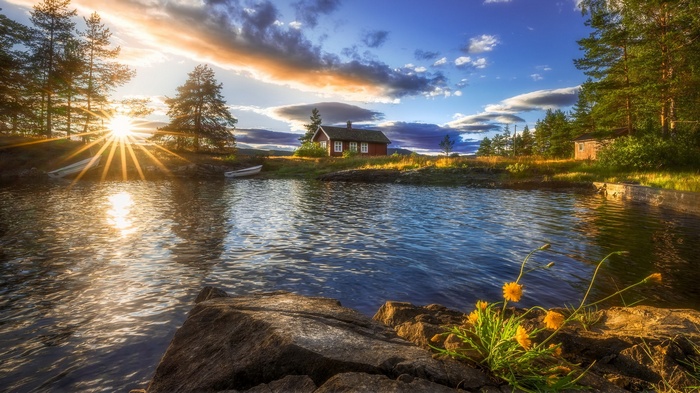 Sunset over a lake with a red cabin and trees